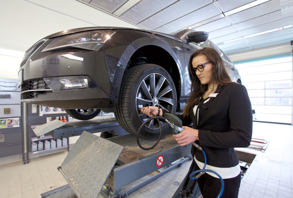 Auszubildende im Autohaus testet den Luftdruck am Autoreifen